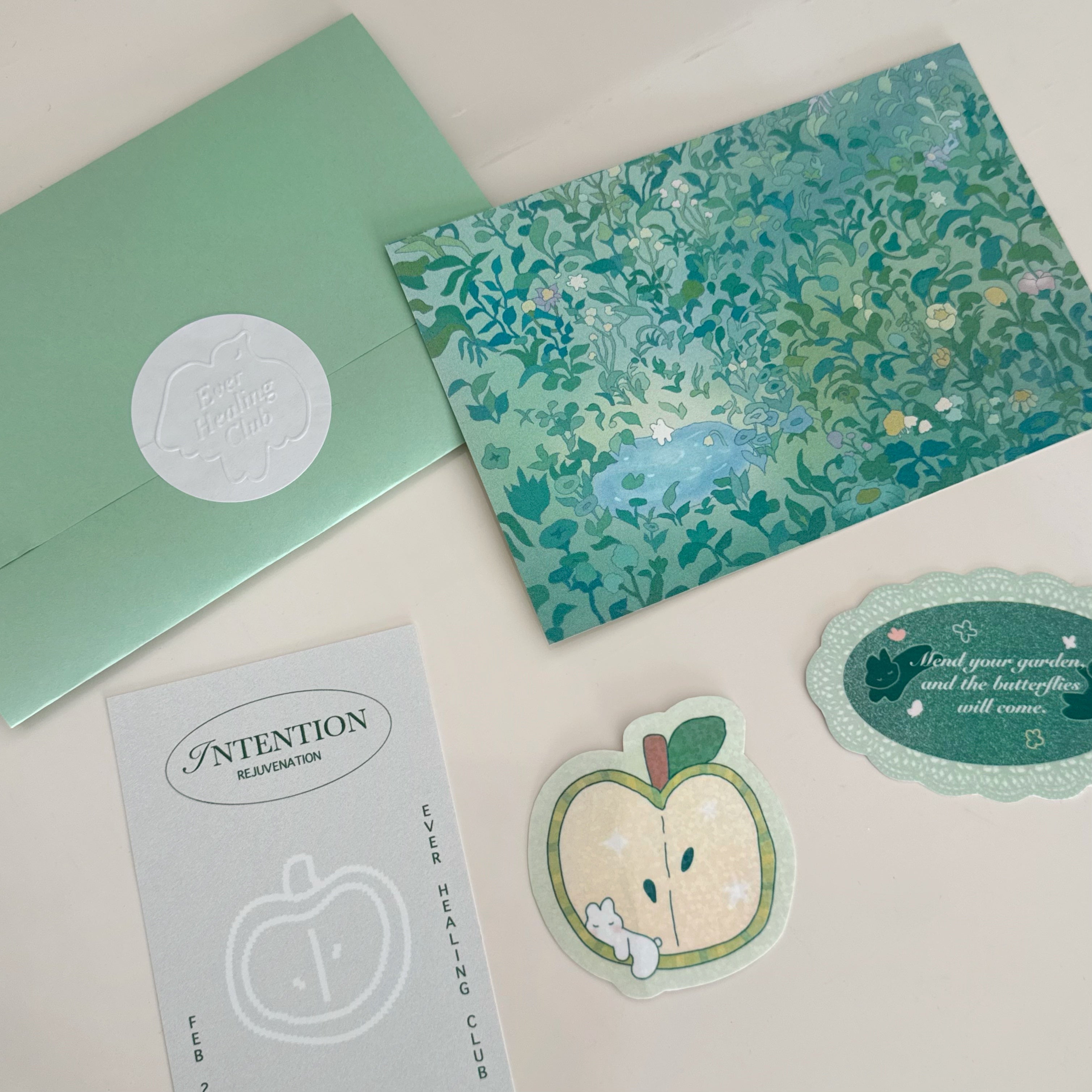 Set of green stationery items including a card, envelope, and stickers on a light background. Snail Mail