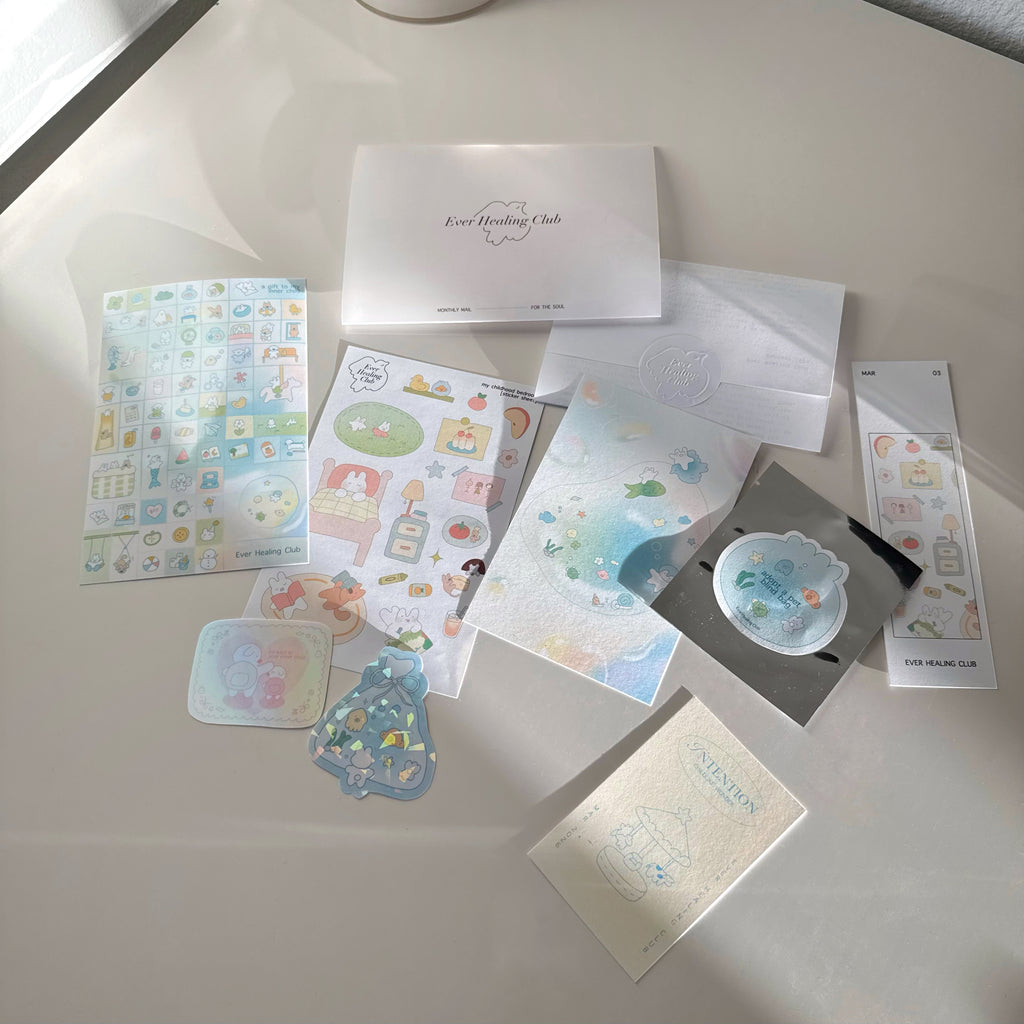 Collection of stationery items including cards, stickers, and envelopes on a light surface. Signature