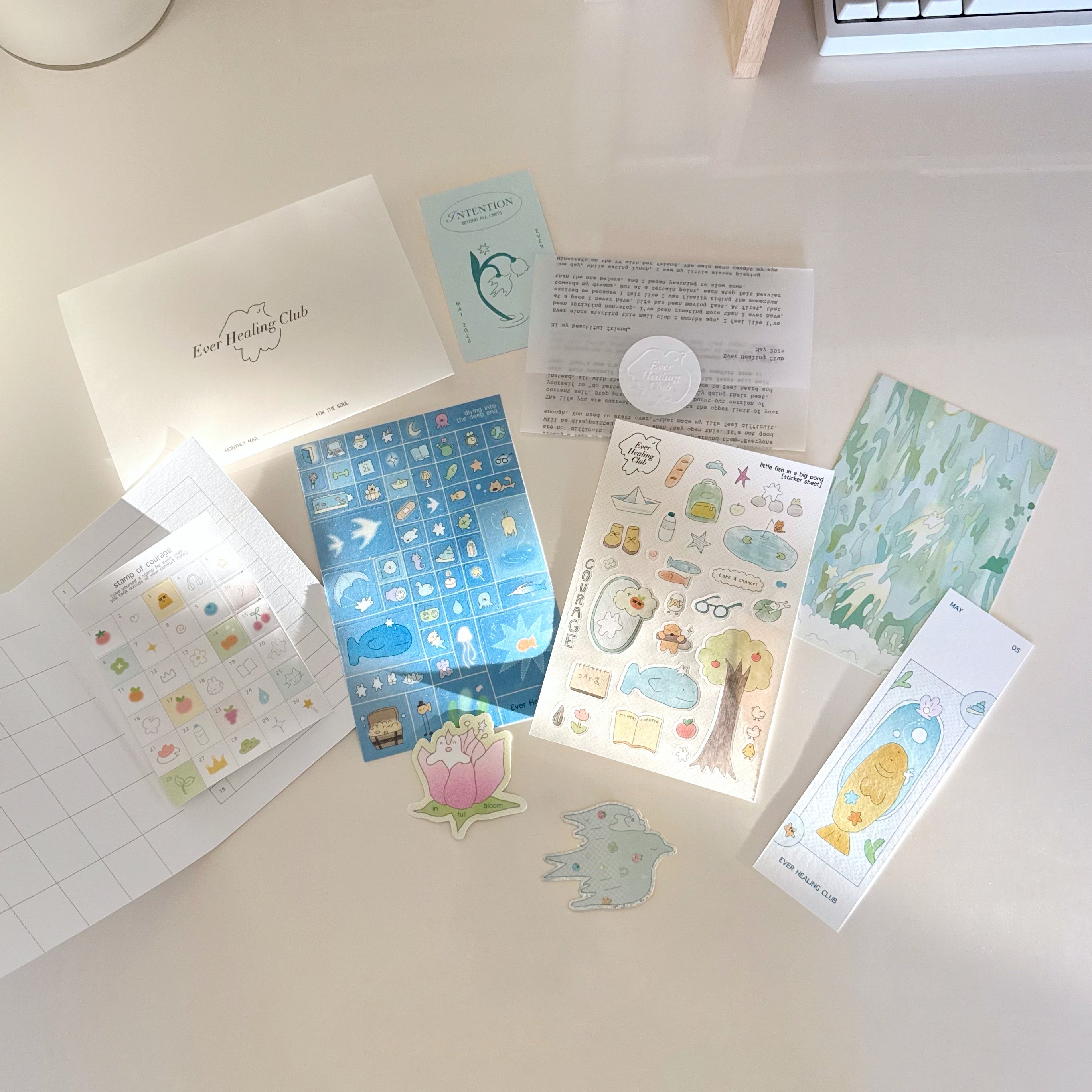 Collection of items from the ever healing club including a 4x6 postcard, vinyl stickers, sticker sheets, activity set, heartfelt letter, intention card, and bookmark. Signature