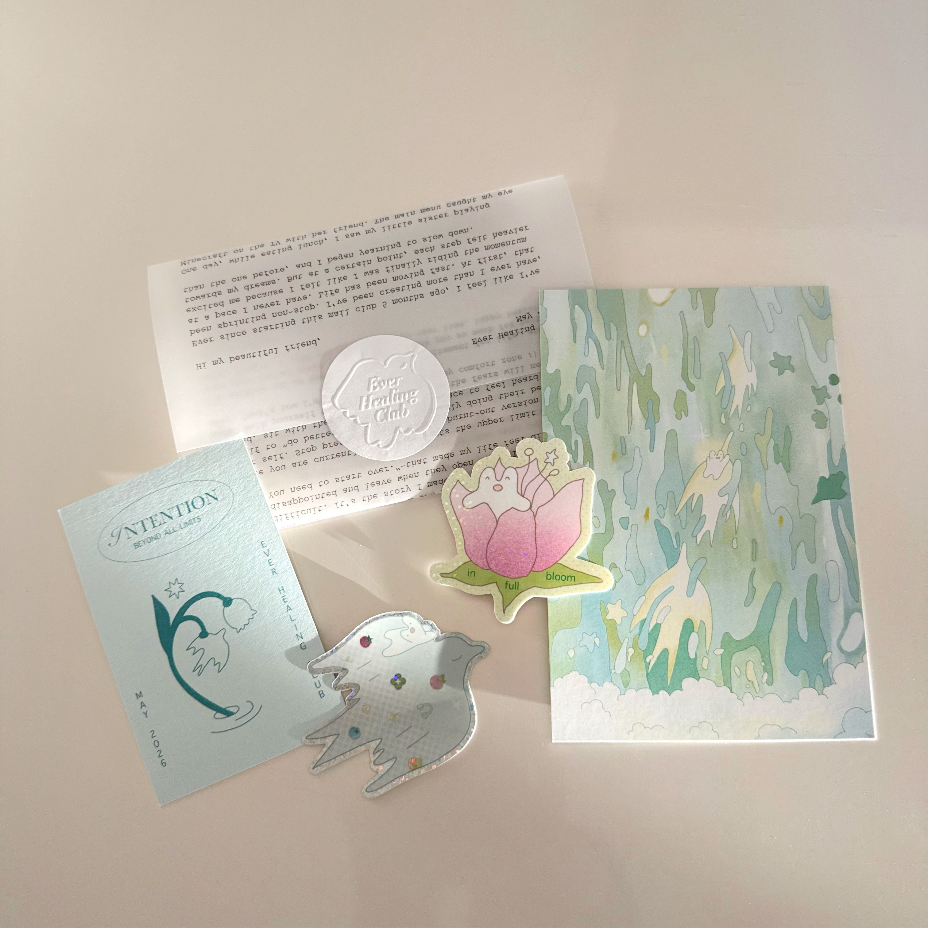 Collection of items from ever healing club including a letter, intention card, postcard, and vinyl stickers on a light background. Snail Mail